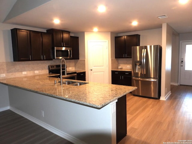 kitchen featuring light hardwood / wood-style floors, light stone countertops, kitchen peninsula, and stainless steel appliances