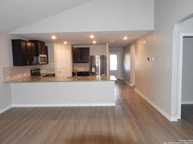 kitchen with sink, tasteful backsplash, kitchen peninsula, vaulted ceiling, and appliances with stainless steel finishes