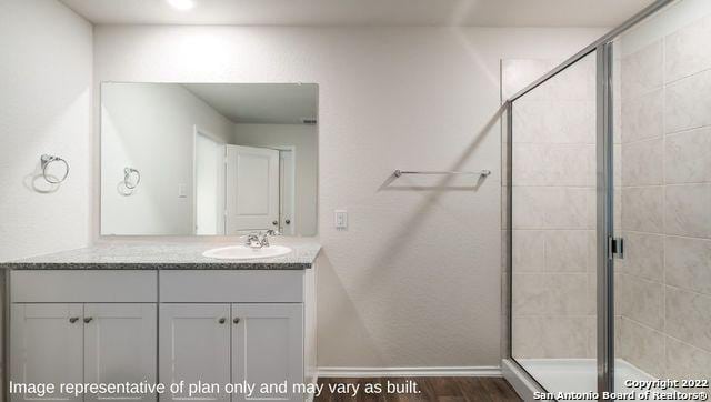 bathroom featuring hardwood / wood-style floors, vanity, and a shower with shower door