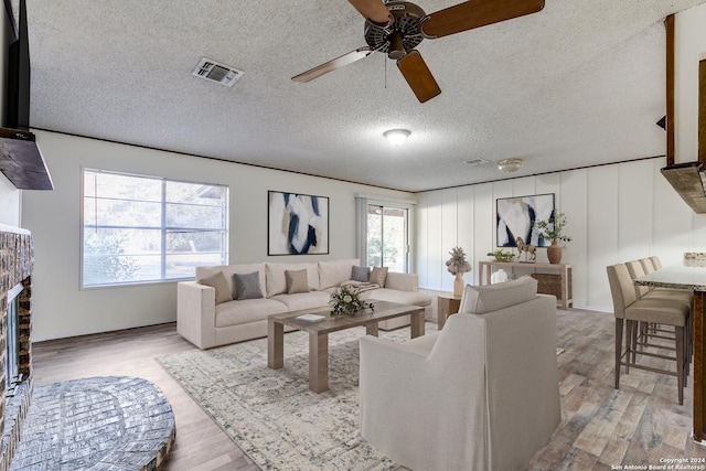 living room with light wood-type flooring, a textured ceiling, and plenty of natural light