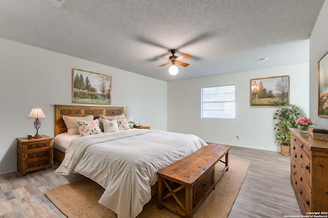 bedroom featuring a textured ceiling, light wood-type flooring, and ceiling fan