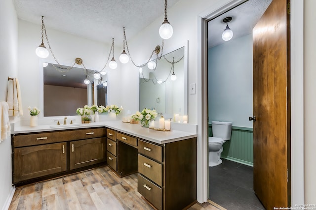 bathroom featuring vanity, toilet, wood-type flooring, and a textured ceiling