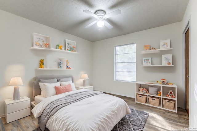 bedroom with ceiling fan, light wood-type flooring, and a textured ceiling