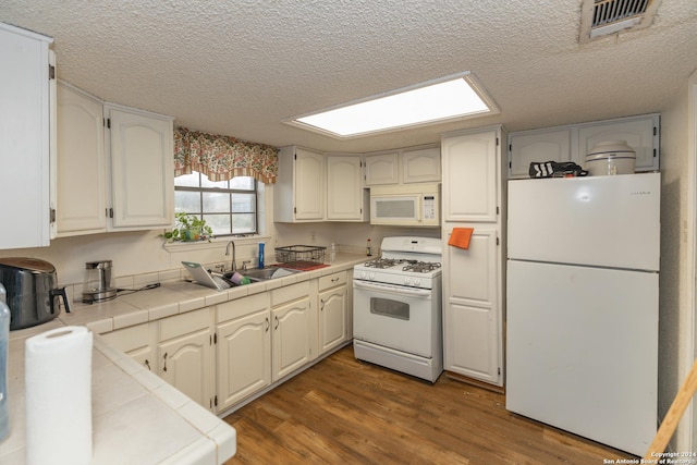 kitchen with white appliances, sink, tile counters, dark hardwood / wood-style flooring, and white cabinetry