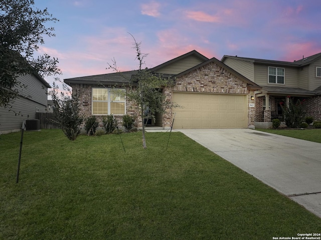 view of front of property with a yard, central AC, and a garage