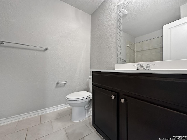 bathroom with a tile shower, vanity, a textured ceiling, tile patterned flooring, and toilet