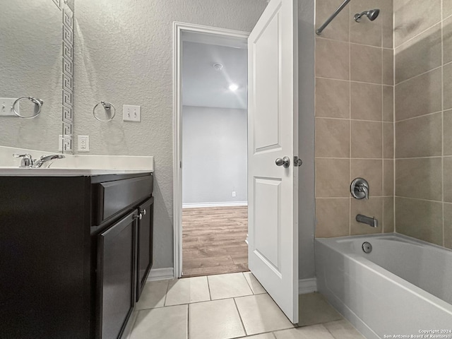 bathroom featuring wood-type flooring, vanity, and tiled shower / bath