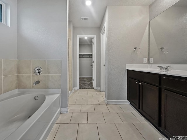 bathroom with tile patterned floors, a tub to relax in, vanity, and a textured ceiling