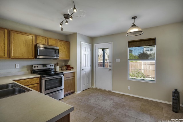 kitchen featuring decorative light fixtures, light tile patterned floors, sink, and appliances with stainless steel finishes