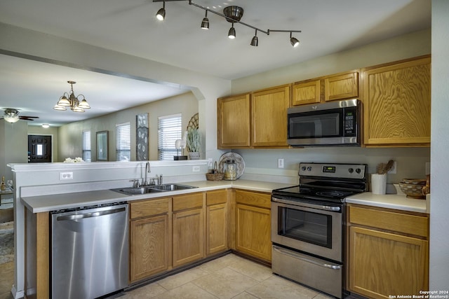 kitchen with ceiling fan with notable chandelier, sink, kitchen peninsula, and stainless steel appliances