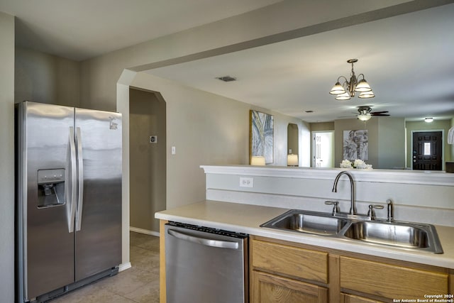 kitchen with ceiling fan with notable chandelier, stainless steel appliances, sink, light tile patterned floors, and decorative light fixtures