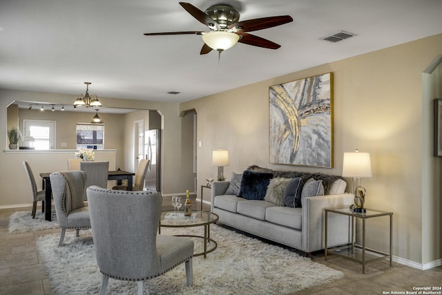 living room featuring ceiling fan with notable chandelier