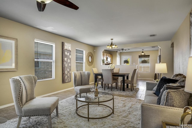 tiled living room featuring ceiling fan with notable chandelier