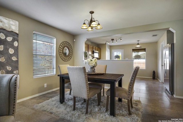 tiled dining room featuring track lighting and a chandelier