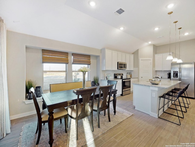 dining room with lofted ceiling and light hardwood / wood-style flooring