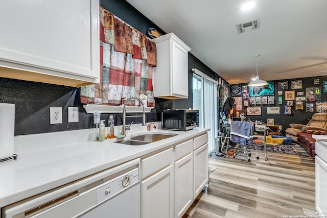 kitchen featuring white dishwasher, sink, decorative light fixtures, light hardwood / wood-style floors, and white cabinetry