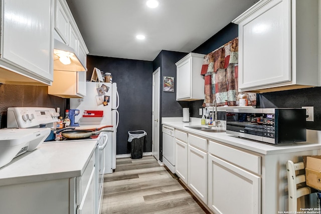 kitchen with white cabinetry, sink, white appliances, and light hardwood / wood-style flooring