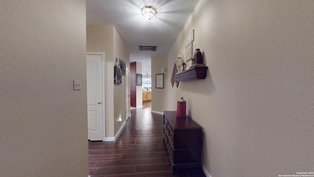 hallway with dark hardwood / wood-style floors and a textured ceiling