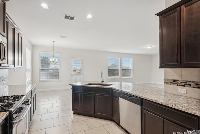 kitchen with pendant lighting, sink, stainless steel appliances, light stone countertops, and light tile patterned flooring