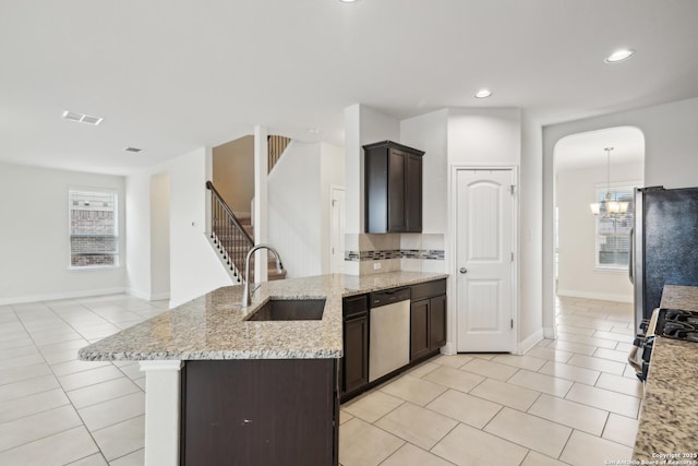 kitchen with light tile patterned flooring, appliances with stainless steel finishes, sink, and light stone counters