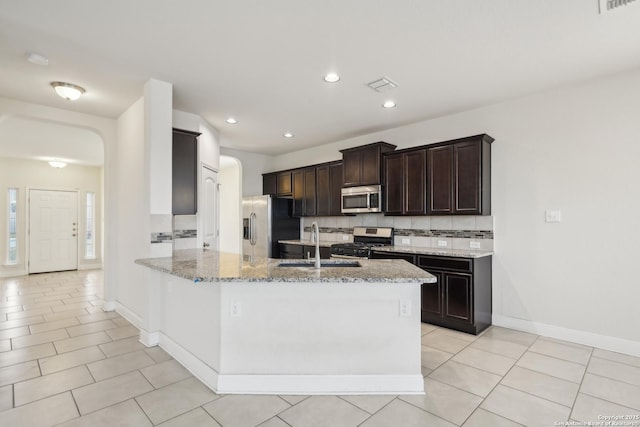 kitchen featuring sink, stainless steel appliances, tasteful backsplash, light stone countertops, and light tile patterned flooring