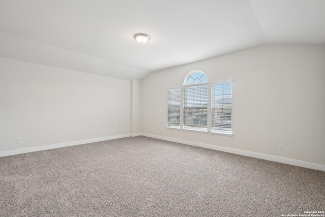 carpeted spare room with lofted ceiling