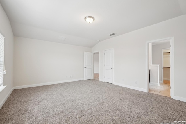 unfurnished bedroom with multiple windows, a walk in closet, light colored carpet, and a closet