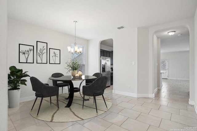 tiled dining area featuring plenty of natural light and a chandelier