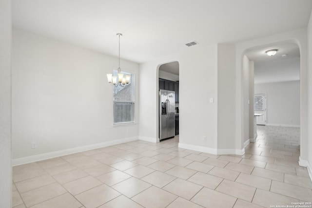 tiled empty room with a notable chandelier