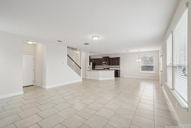 unfurnished living room with light tile patterned flooring and an inviting chandelier