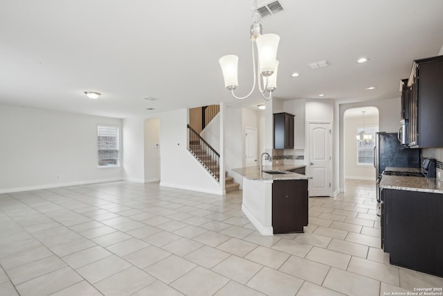 kitchen with dark brown cabinetry, light stone countertops, a chandelier, and decorative backsplash