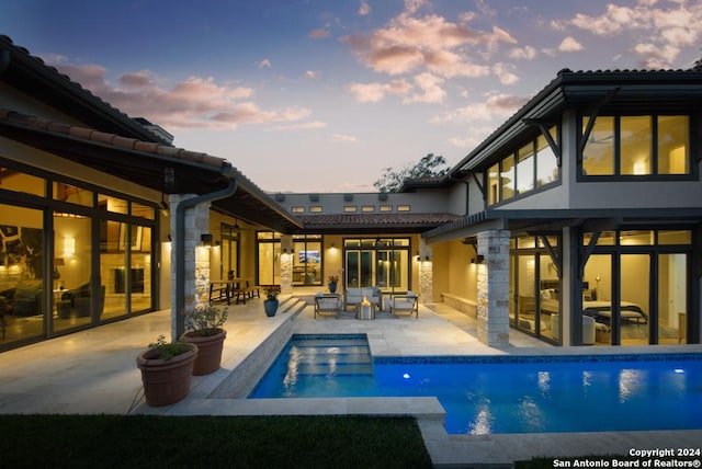 pool at dusk featuring a patio area