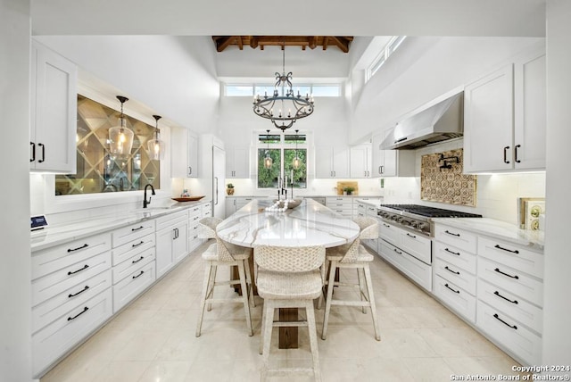 kitchen featuring white cabinetry, a breakfast bar, a center island, and ventilation hood