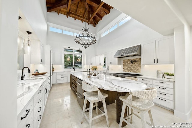 kitchen with white cabinets, a large island, beamed ceiling, and extractor fan