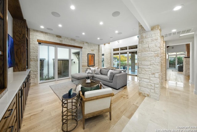 living room with ornate columns, light hardwood / wood-style flooring, and a healthy amount of sunlight