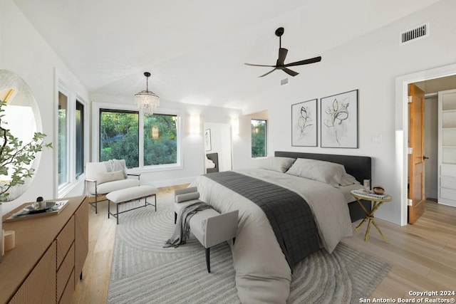 bedroom featuring ceiling fan with notable chandelier, light hardwood / wood-style flooring, and vaulted ceiling