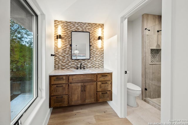 bathroom featuring vanity, hardwood / wood-style flooring, toilet, tasteful backsplash, and an enclosed shower