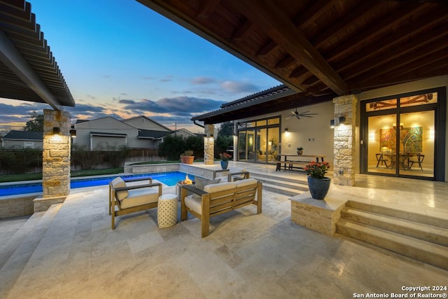 pool at dusk with a patio and ceiling fan