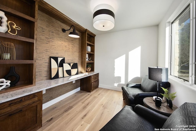 sitting room featuring light hardwood / wood-style flooring, built in desk, and built in features