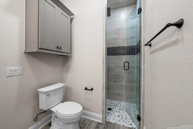 bathroom featuring wood-type flooring, toilet, and an enclosed shower