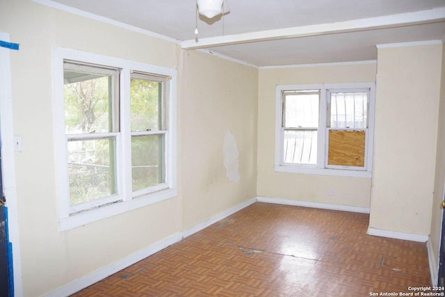 empty room with a wealth of natural light, ornamental molding, and parquet flooring