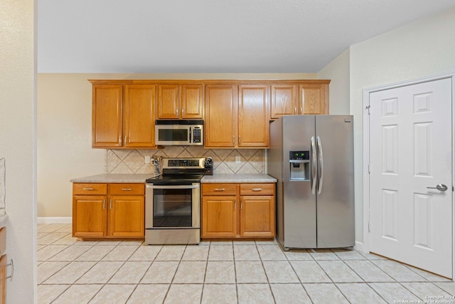 kitchen featuring decorative backsplash, light tile patterned flooring, and stainless steel appliances