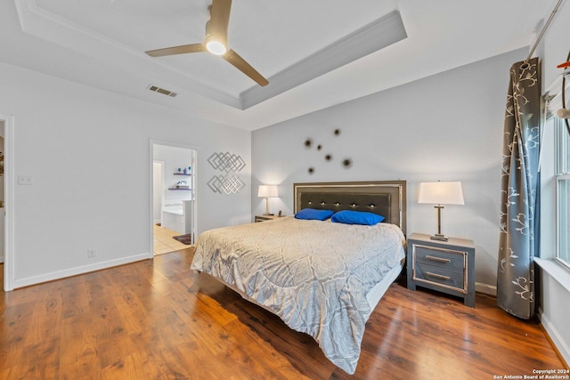 bedroom with hardwood / wood-style floors and a tray ceiling