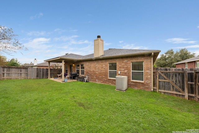 rear view of house with a yard, cooling unit, and a patio