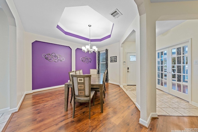 dining room with a chandelier, french doors, and light hardwood / wood-style flooring