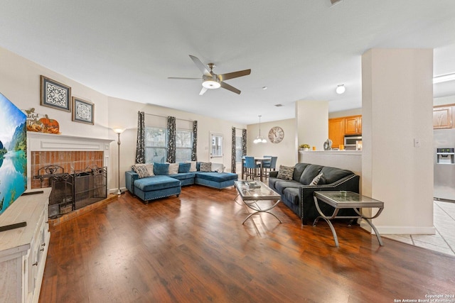 living room with a fireplace, light hardwood / wood-style flooring, and ceiling fan