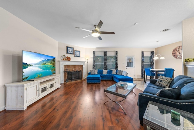 living room featuring ceiling fan with notable chandelier, dark hardwood / wood-style flooring, and a tile fireplace