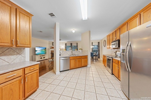 kitchen with tasteful backsplash, sink, light tile patterned floors, and stainless steel appliances