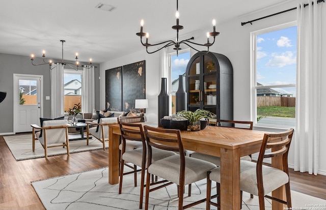 dining space with wood-type flooring, a wealth of natural light, and a chandelier