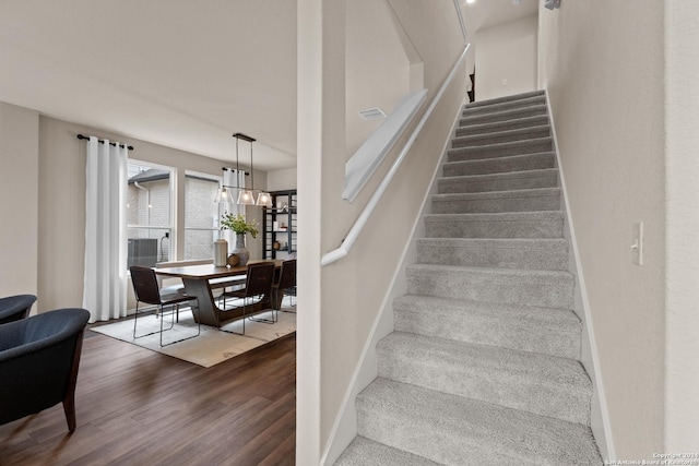 stairway featuring hardwood / wood-style floors and a notable chandelier